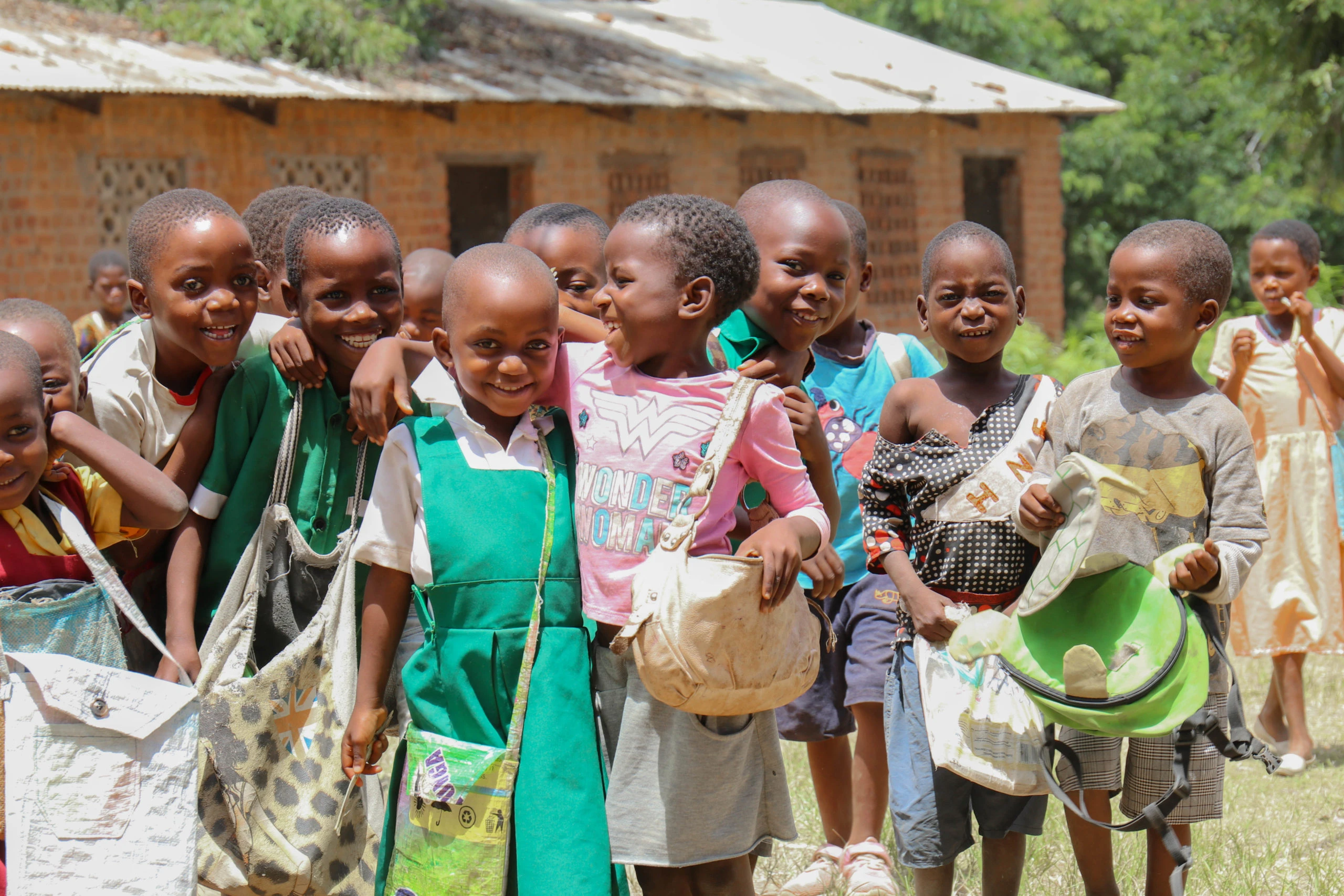 Een groep lachende kinderen met schooltassen.